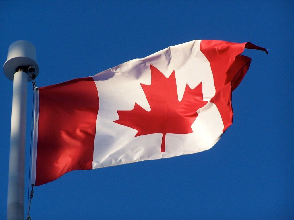 Canadian flag waving against a blue sky